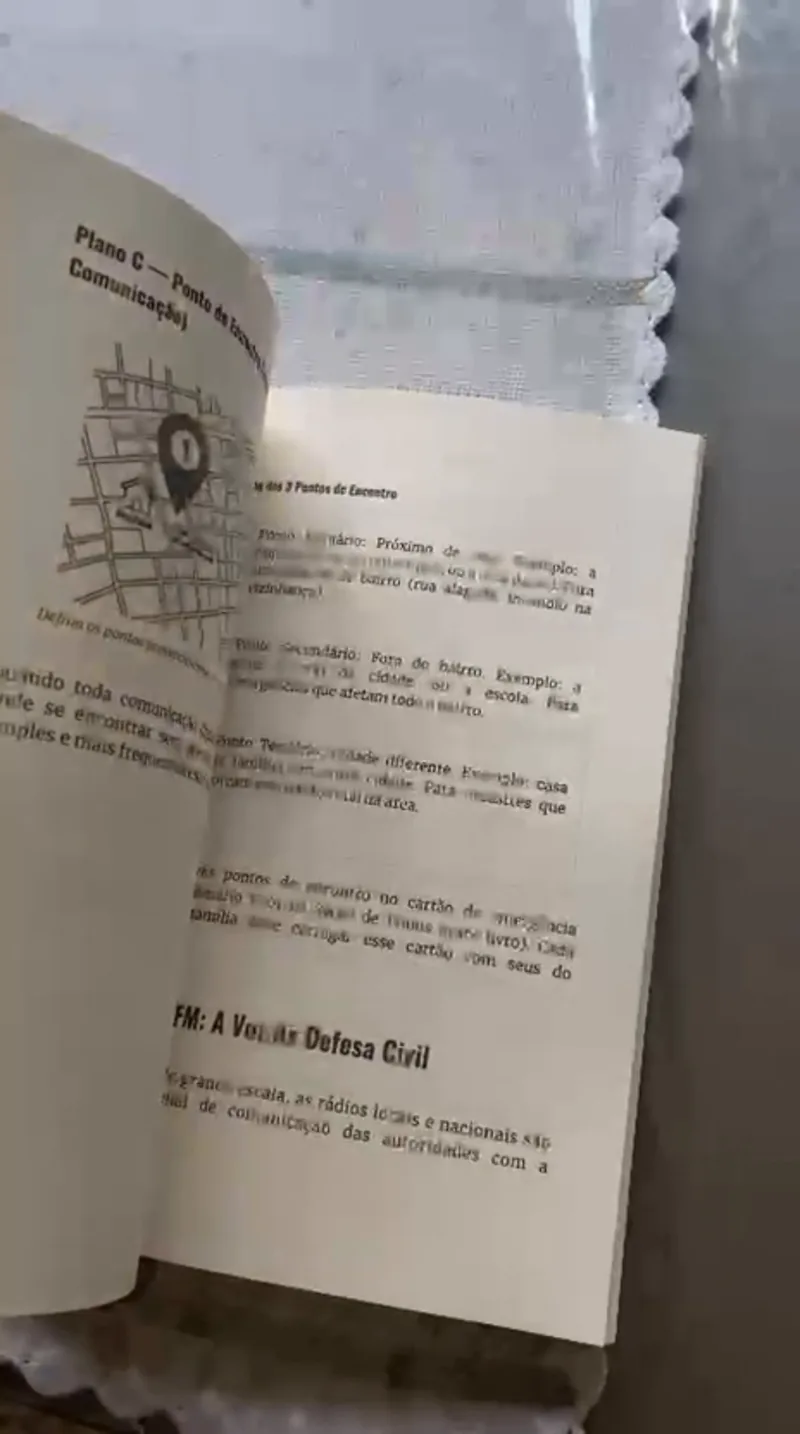 Página do livro com um mapa de bairro marcando os pontos de encontro da família e o trecho sobre o rádio FM da Defesa Civil.